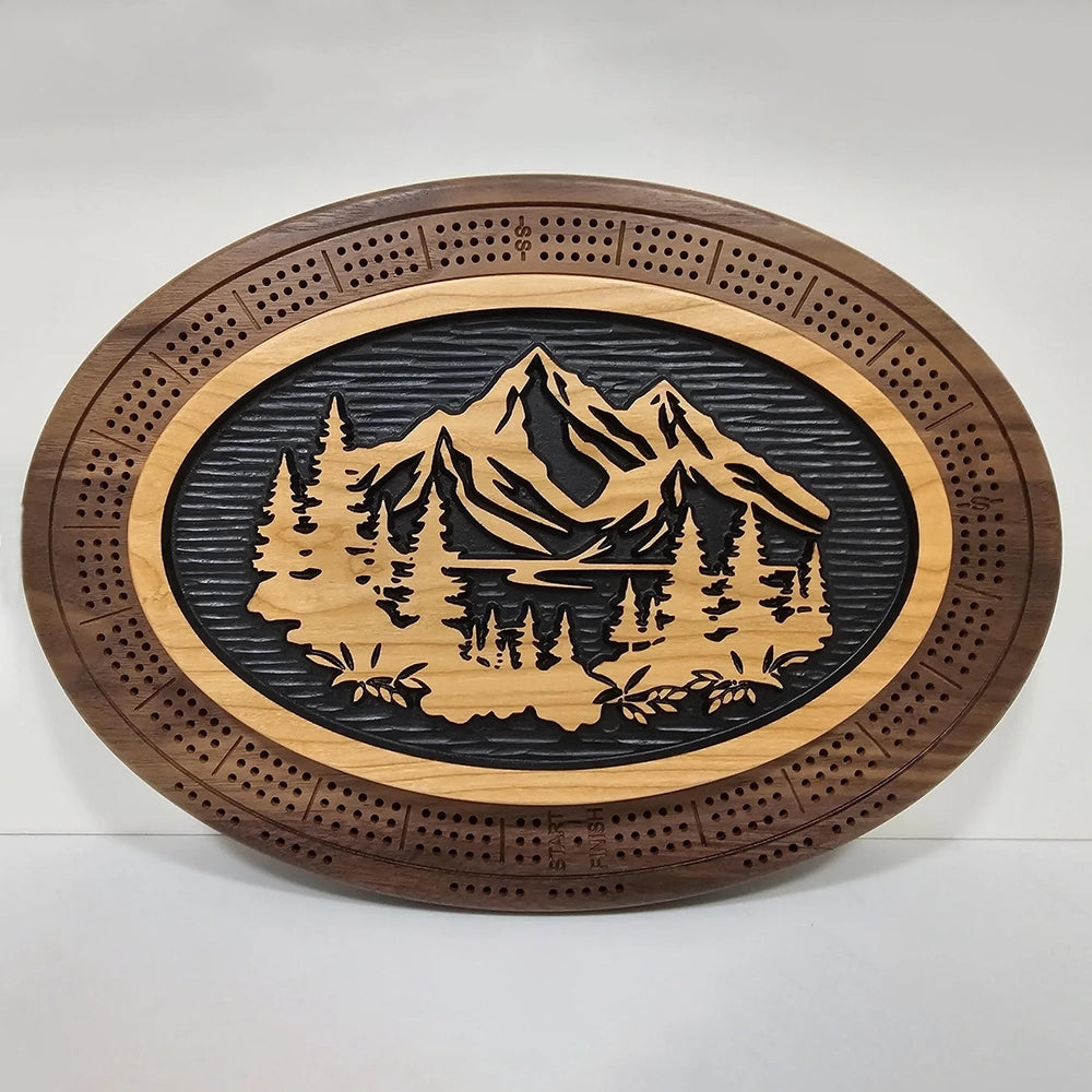 A handcrafted cribbage board featuring a scenic design of mountains, flowing water, and lush trees.