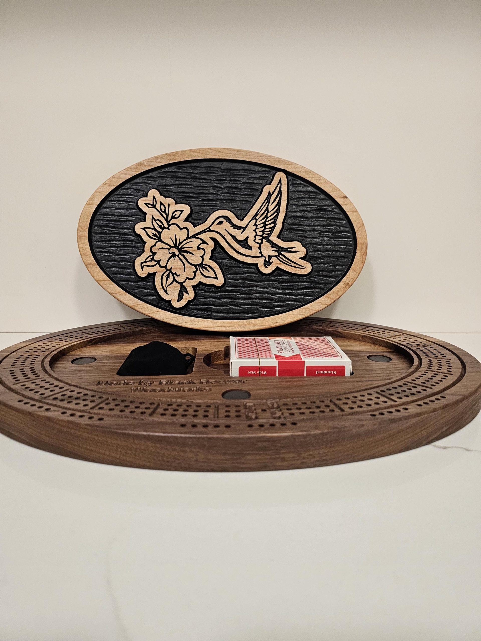 Handcrafted oval cribbage board featuring decorative hummingbird and blossom engraving on black inlay